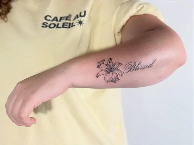 Lilien-Tattoo mit Schriftzug auf dem Arm